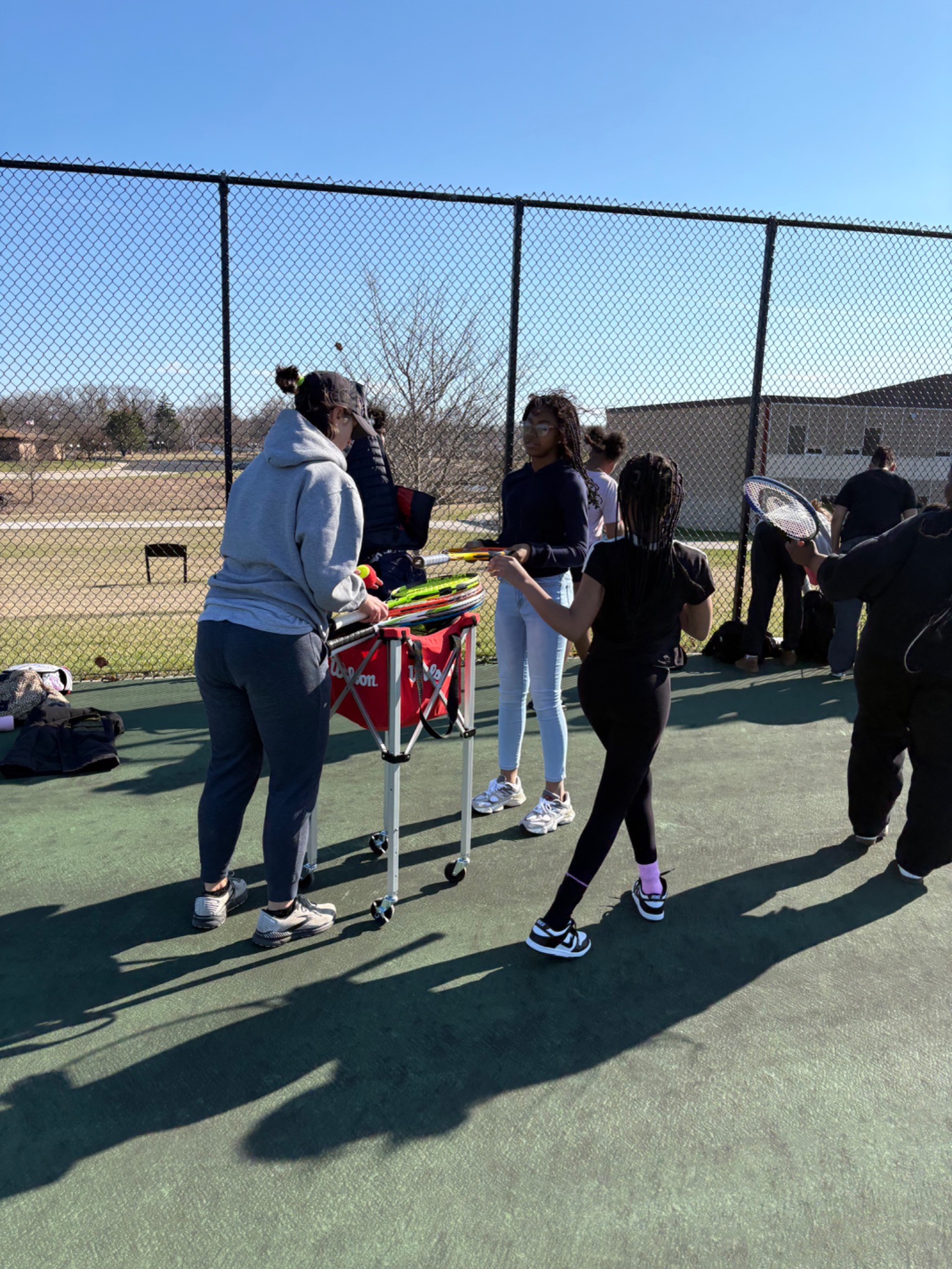 Students selecting tennis rackets on the court at Brown Deer Middle and High School
