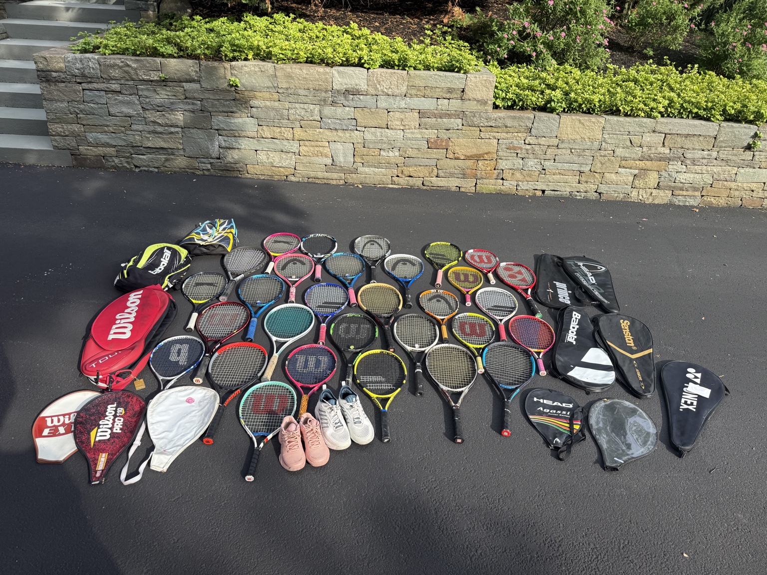 Collected tennis rackets, bags, and shoes arranged for donation