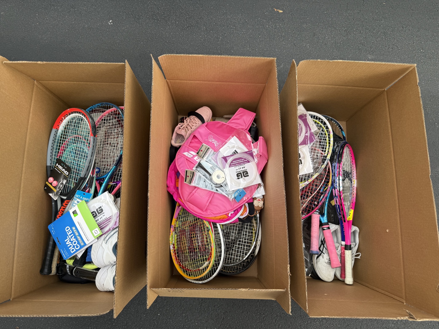 Three boxes packed with donated rackets and tennis gear